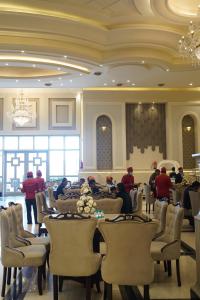 a dining room with tables and chairs and people in a room at Hotel The Grand Mirage in Bathinda