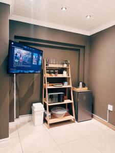 a room with a flat screen tv and a shelf at Lemon & Blue Guest House in Welkom