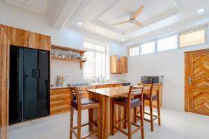 a kitchen with a wooden table and a black refrigerator at Bahari Beach Front Villa in Mdudu Mkubwa
