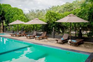 a group of chairs and umbrellas next to a pool at Lavendish Country Resort in Dambulla