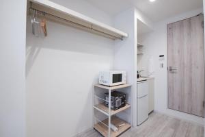 a small white kitchen with a microwave on a shelf at Boa Sorte Hotel AD0515 in Tokyo +77 photos