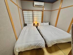 two beds in a small room with a window at HOTTOSTAY OoGANE in Nagoya