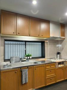 a kitchen with wooden cabinets and a sink at HOTTOSTAY OoGANE in Nagoya