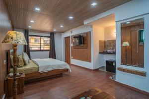 a bedroom with a bed and a kitchen at Peaks n Pines in Nainital