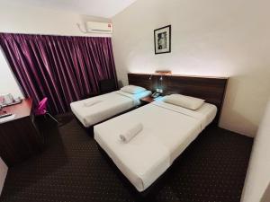 two beds in a hotel room with purple curtains at Hotel Yt Midtown Kuala Terengganu in Kuala Terengganu +28 photos
