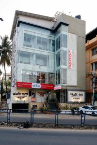 a large building with a car parked in front of it at Pearl Inn in Dhārwād