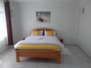 a bedroom with a bed with yellow and white sheets at countrysidegatewayapartments in Nyeri