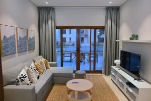 a living room with a couch and a tv at Wateera Jebel Sifah-Beachfront & Golf View in As Sīfah