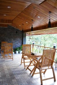 three wooden chairs and a table on a patio at Arcelia Cottage, Cozy Villa in Nainital in Nainital
