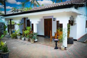 a white house with potted plants in front of it at Guru Guest House in Trincomalee