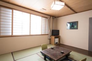 a living room with a table and a tv at Yachi Onsen in Towada