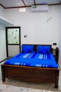 a bed in a room with blue pillows at Guru Guest House in Trincomalee