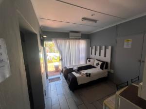 a small bedroom with a bed and a window at Martinique Guesthouse in Kathu