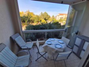 a patio with a table and chairs and a large window at Soleil d'or à St Aygulf in Fréjus