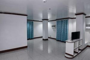 a room with a tv on a table and columns at La Elliana Hotel & Restaurant, Inc. in Laoag