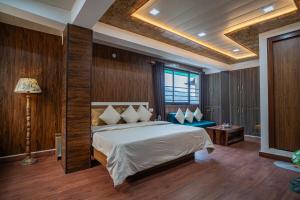 a bedroom with a bed and a table and a lamp at Peaks n Pines in Nainital