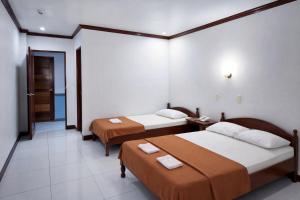 a hotel room with two beds and a hallway at La Elliana Hotel & Restaurant, Inc. in Laoag