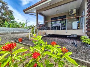 a house with a balcony with red flowers at Teahupo'o Lodge Tahiti - Studio Moana, lagon et quai en face - Canoës inclus in Teahupoo