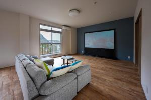 a living room with a couch and a flat screen tv at Umi no SOBA 伊豆 - BBQ & Sauna in Ito