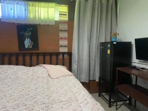 a bedroom with a bed and a desk and a television at Arku’s House in Chiang Mai