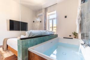 a bathroom with a tub and a bed and a television at Palazzo Italia Suites in Bari