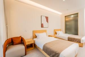 a hotel room with two beds and a chair at Beijing Daxing Apartment in Ban Doung