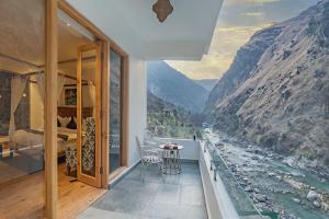 a bedroom with a balcony with a view of a river at Echor Palm Bliss Resort & Spa, Kasol in Kasol