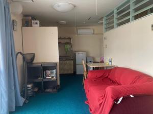 a room with a red bed and a kitchen at BIGJOY INN Hirokouji in Miyako-jima