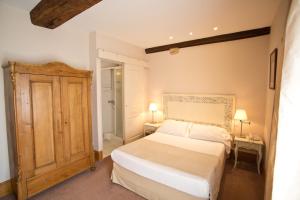 a bedroom with a white bed and a wooden cabinet at Hotel l'Orée Des Vignes in Gilly-lès-Cîteaux