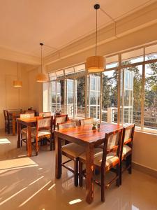 a dining room with wooden tables and chairs and windows at Barylia in Mawlyngkhung