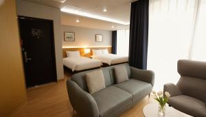 a hotel room with a couch and two beds at Kwangsu Hotel Haeundae in Busan