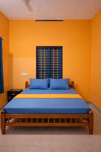 a bedroom with a bed with blue sheets and a window at Casa Tangerina in Varkala