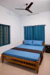 a bedroom with a blue bed with a ceiling fan at Casa Tangerina in Varkala