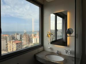 a bathroom with a window and a sink with a view at Maison by Grey Pearls Suites in Mīnāʼ al ‘Atīqah +11 photos