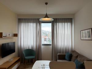 a living room with a couch and a window at Maison by Grey Pearls Suites in Mīnāʼ al ‘Atīqah