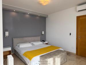 a bedroom with a large bed with a yellow blanket at Maison by Grey Pearls Suites in Mīnāʼ al ‘Atīqah