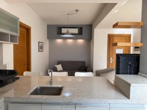 a kitchen with a sink and a living room at Maison by Grey Pearls Suites in Mīnāʼ al ‘Atīqah