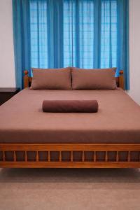 a bed with a wooden frame and blue curtains at Casa Tangerina in Varkala +3 photos