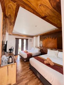 two beds in a hotel room with wooden ceilings at Puyo Suites Homestay in General Luna