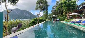 a pool at a resort with mountains in the background at The Cocoon - Glamping at Karuna El Nido in El Nido
