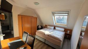 a small bedroom with a bed and a table and a window at Pension Sandra in Neuharlingersiel +14 photos