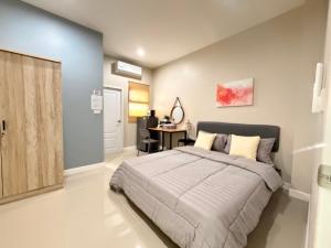 a bedroom with a large bed and a desk at Cha V Place Buriram - ชาวีเพลส บุรีรัมย์ in Ban Yang