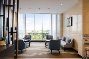 a waiting room with chairs and tables and windows at Fairfield by Marriott Agra in Agra