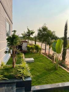 a garden with trees and a building and a yard with grass at Aacasa Living Resorts in Shamshabad +5 photos