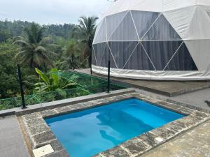 a marquee with a blue pool and a tent at Sinharaja Geo Dome in Nelluwa