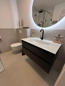 a bathroom with a sink and a toilet and a mirror at Apartment Wörtherseeliebe in Pörtschach am Wörthersee +14 photos