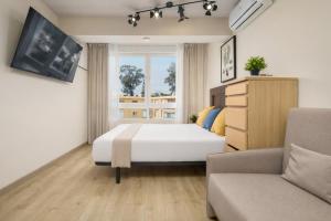a bedroom with a bed and a couch and a window at Beachfront Design LUX Studio Apartment in Estepona