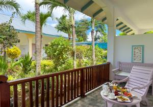 a porch with two chairs and a table with food on it at Coral Apartments in La Digue