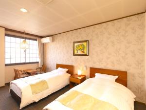 a bedroom with two beds and a table and a window at Hotaru no Yado Sendou in Yufu