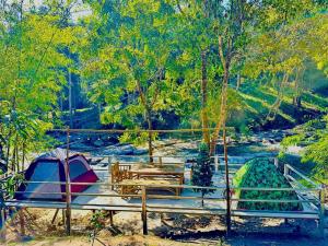 a picnic table with a tent and a river at Ban Kham Kee Homestay in Chiang Mai